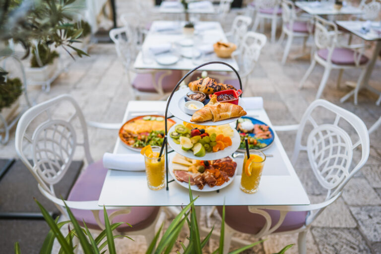 Three-tier breakfast stand with pastries, fresh fruit, cheeses and cured meats.