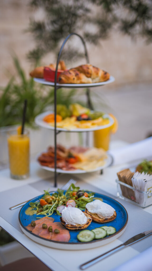 Three-tier breakfast stand with pastries, fresh fruit, cheeses and cured meats.