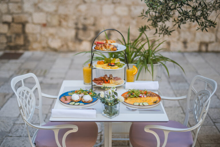 Three-tier breakfast stand with pastries, fresh fruit, cheeses and cured meats.