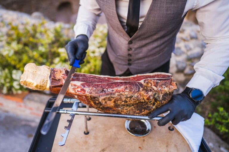 A waiter cutting prosciutto