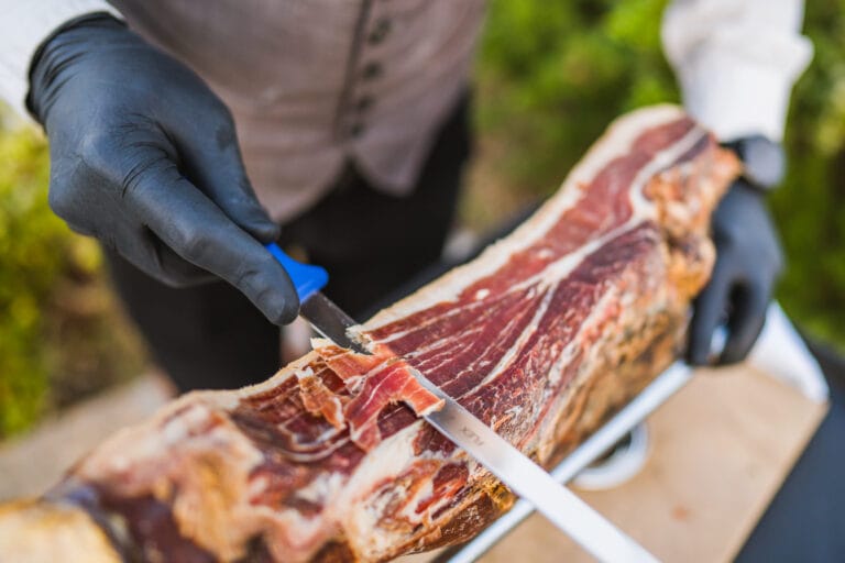 A waiter cutting prosciutto