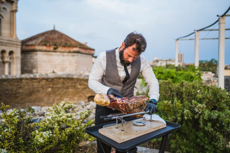 A waiter cutting prosciutto with the Cathedral in view