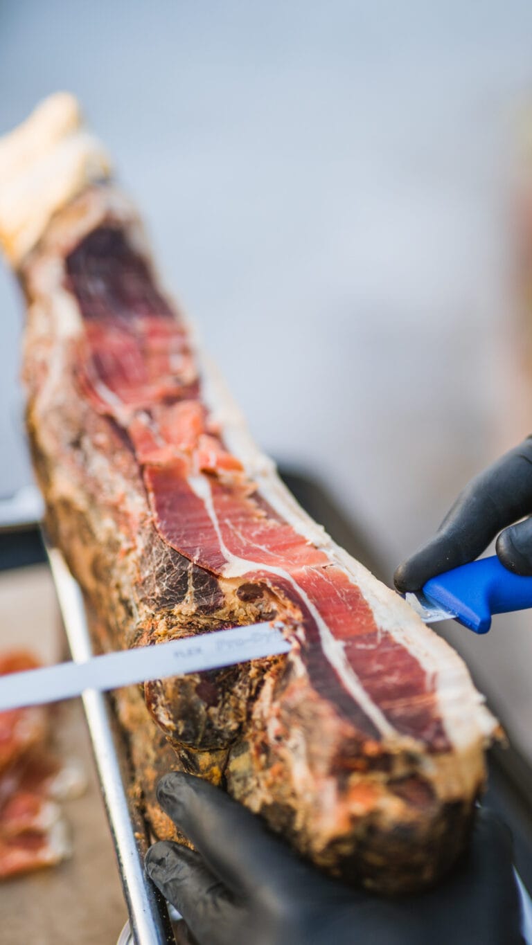 A waiter cutting prosciutto