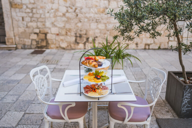 Three-tier breakfast stand with pastries, fresh fruit, cheeses and cured meats.