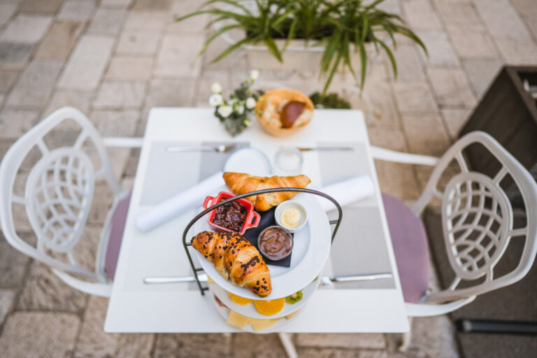 Three-tier breakfast stand with pastries, fresh fruit, cheeses and cured meats.
