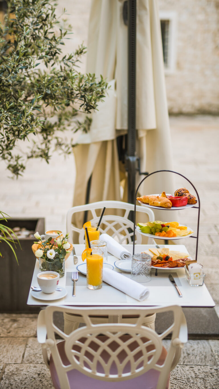 Three-tier breakfast stand with pastries, fresh fruit, cheeses and cured meats.