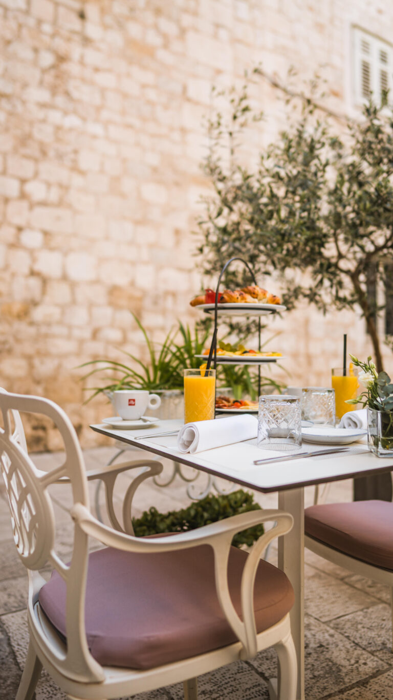 Three-tier breakfast stand with pastries, fresh fruit, cheeses and cured meats.