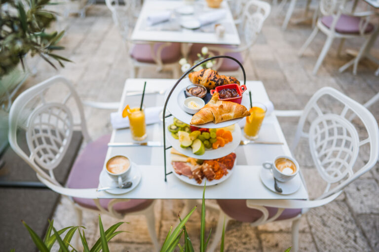 Three-tier breakfast stand with pastries, fresh fruit, cheeses and cured meats.