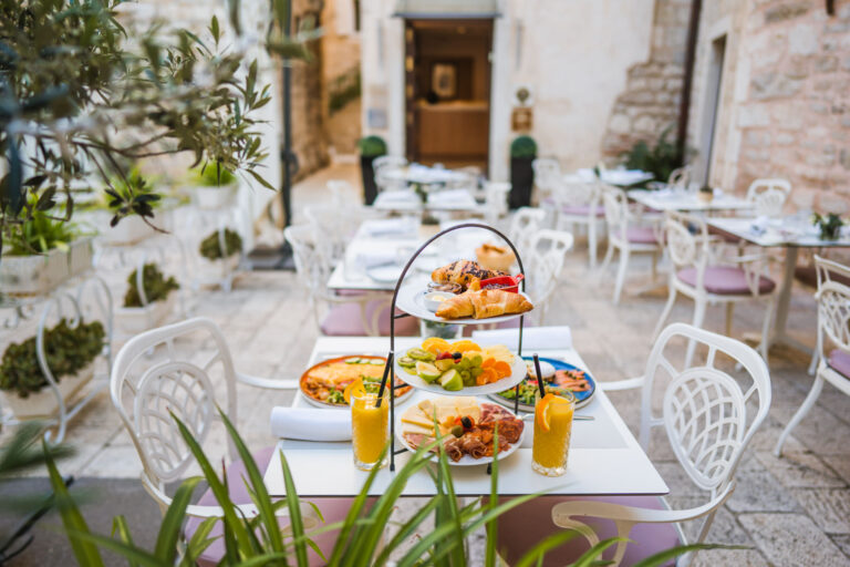 Three-tier breakfast stand with pastries, fresh fruit, cheeses and cured meats.