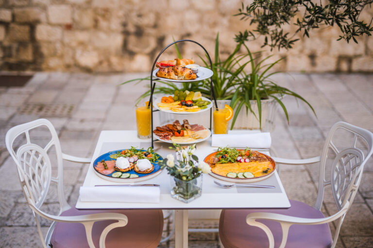 Three-tier breakfast stand with pastries, fresh fruit, cheeses and cured meats.