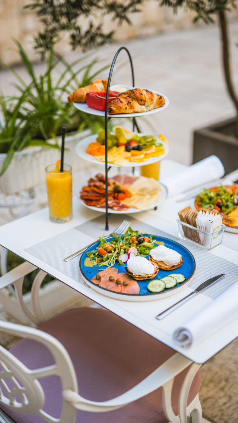 Three-tier breakfast stand with pastries, fresh fruit, cheeses and cured meats.