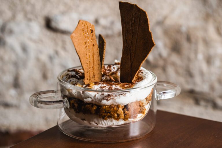 Creamy layered dessert topped with cocoa powder and crisp caramel shards.